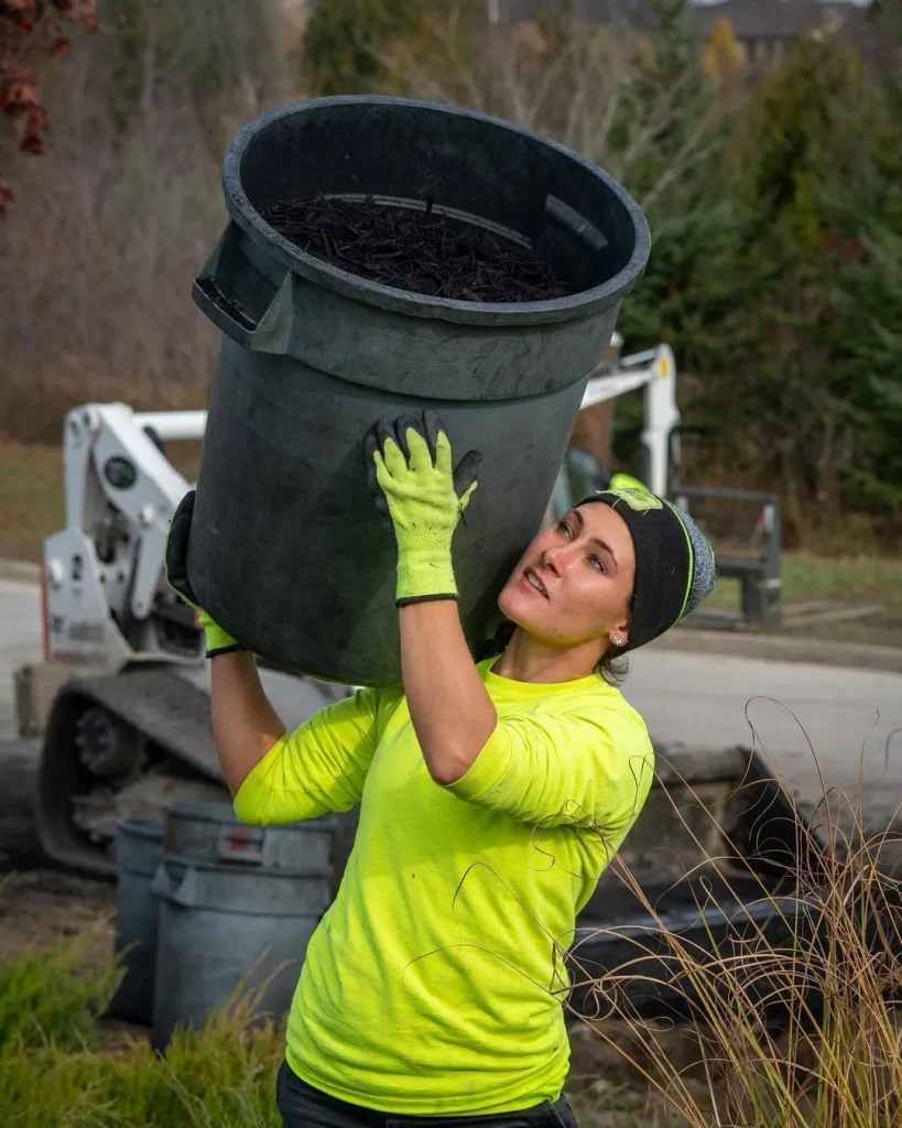 a landscaper carries a large bucket