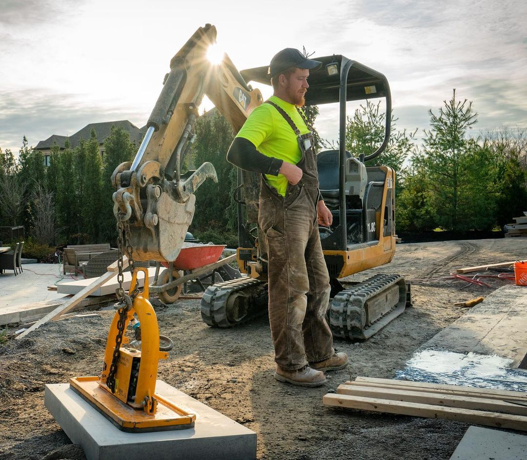A landscaper successfully using his new CAT 303 mini hydraulic excavator to help lift a heavy slab