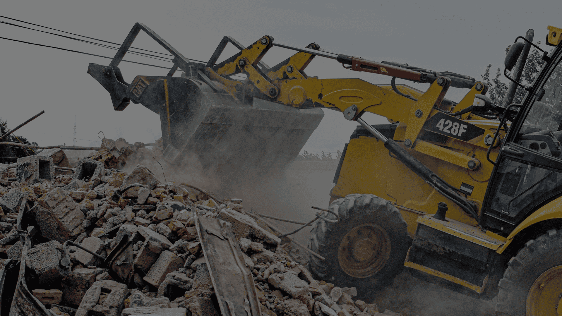 A yellow digger truck climbing a pile of concrete debris